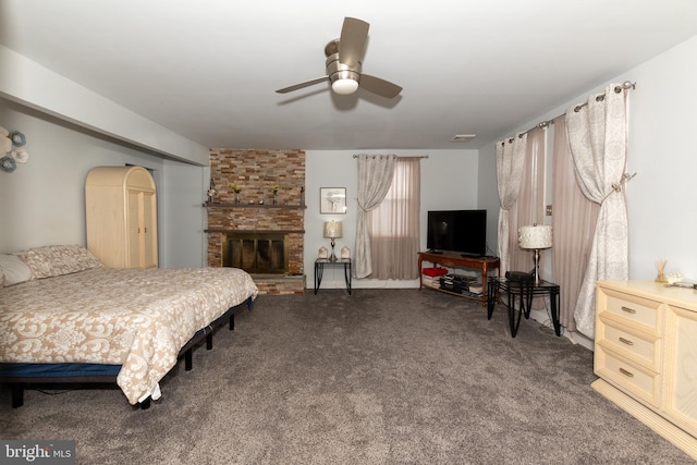 carpeted bedroom with ceiling fan and a large fireplace