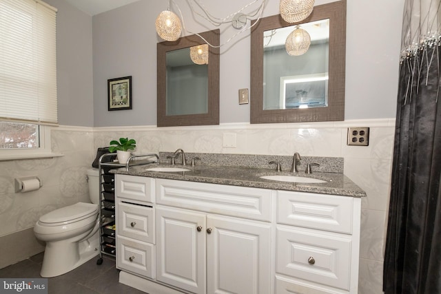 bathroom with vanity, toilet, tile walls, and tile patterned flooring