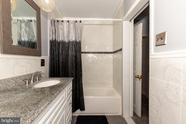 bathroom with shower / bath combo with shower curtain, tile walls, tile patterned floors, and vanity