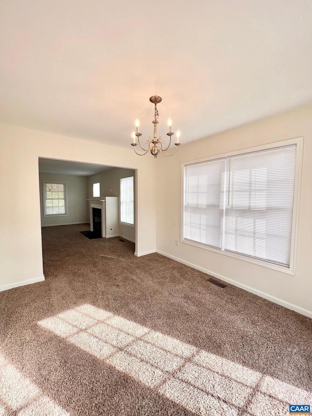 carpeted spare room featuring an inviting chandelier