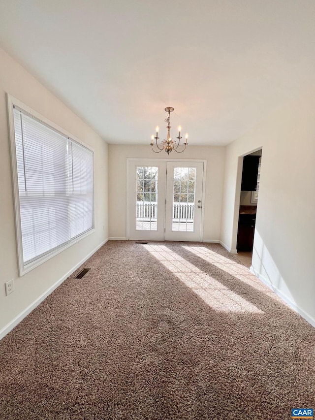 unfurnished room featuring carpet floors and a notable chandelier