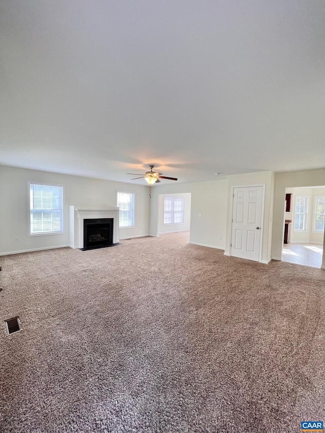 unfurnished living room with ceiling fan, carpet, and a healthy amount of sunlight