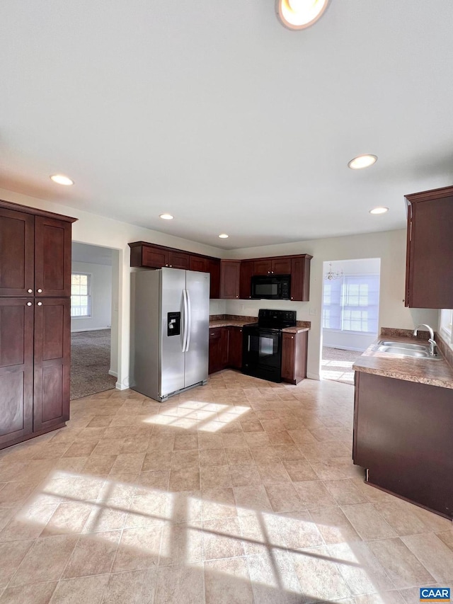 kitchen with black appliances, a healthy amount of sunlight, sink, and light colored carpet