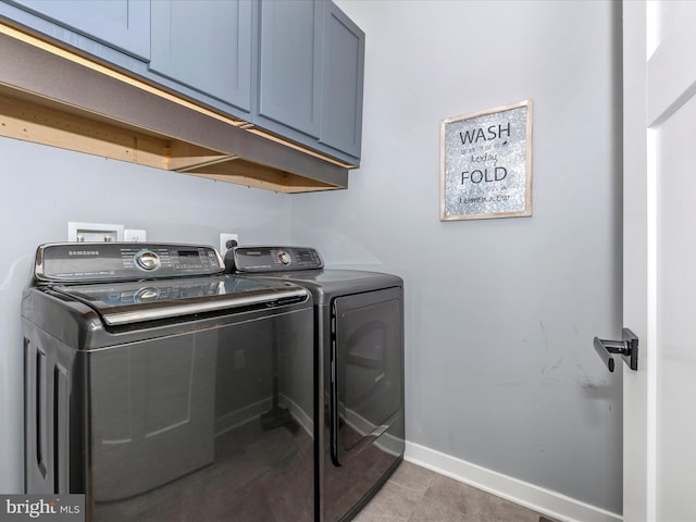 clothes washing area featuring washing machine and dryer and cabinets