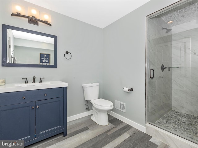 bathroom with wood-type flooring, vanity, toilet, and walk in shower