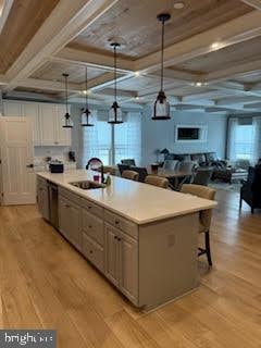 kitchen featuring a spacious island, sink, hanging light fixtures, and coffered ceiling