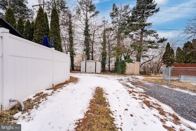 yard covered in snow with a storage unit