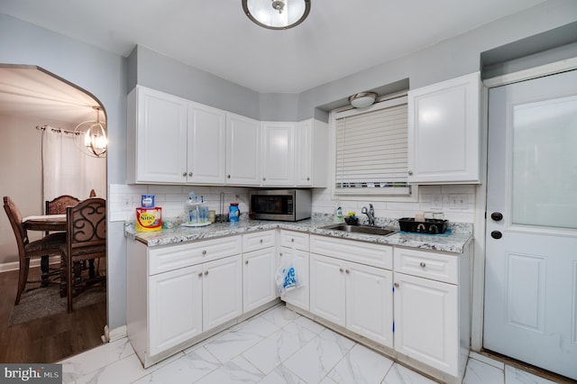 kitchen with decorative backsplash, sink, and white cabinets