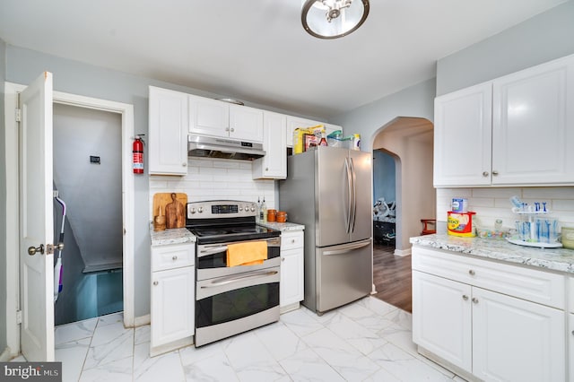 kitchen featuring light stone countertops, white cabinets, decorative backsplash, and appliances with stainless steel finishes