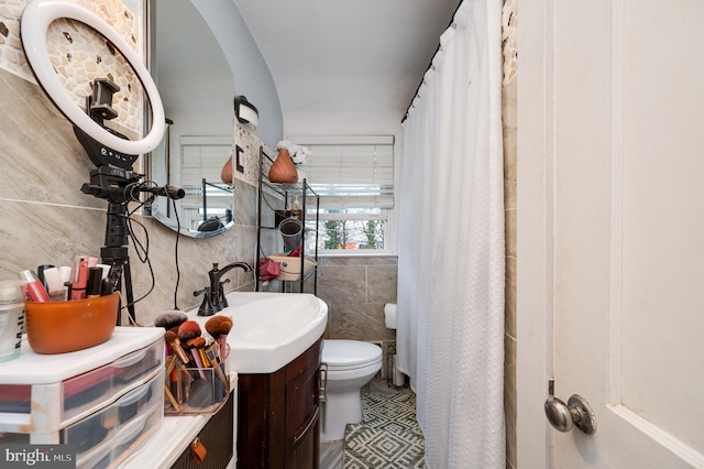 bathroom with tile walls, toilet, vanity, and a shower with shower curtain