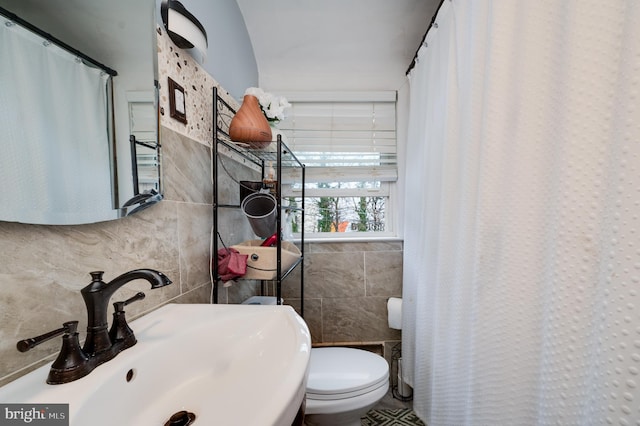 bathroom with toilet, tile walls, sink, and tasteful backsplash