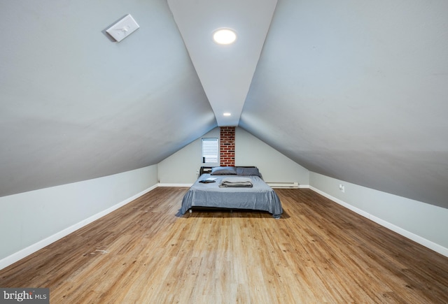 unfurnished bedroom with light hardwood / wood-style floors, baseboard heating, and vaulted ceiling