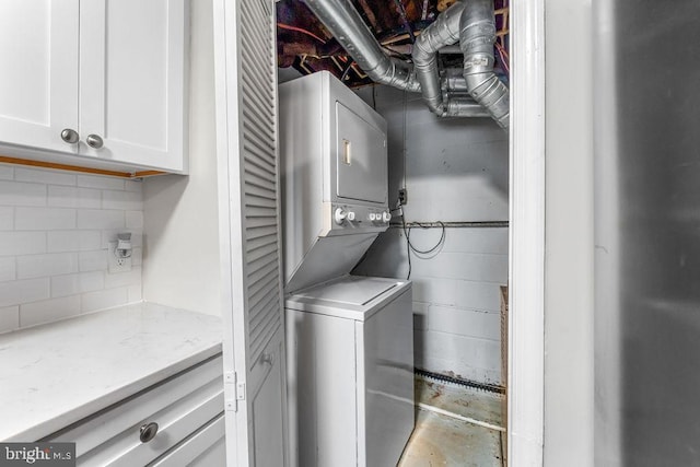 laundry room with stacked washer and clothes dryer and cabinets