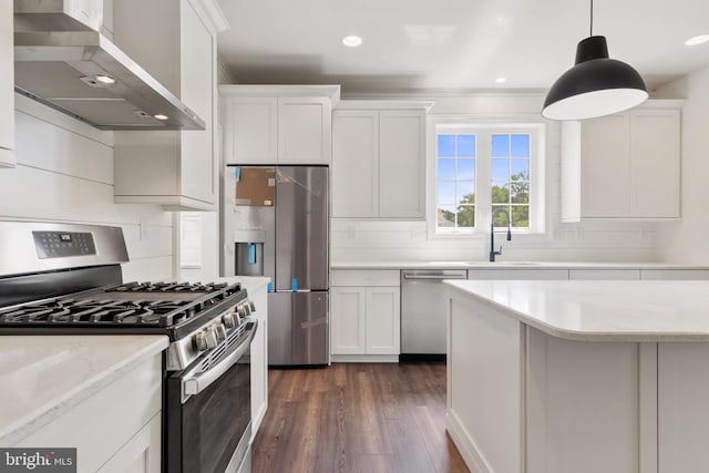 kitchen with white cabinets, appliances with stainless steel finishes, wall chimney exhaust hood, dark wood-type flooring, and sink