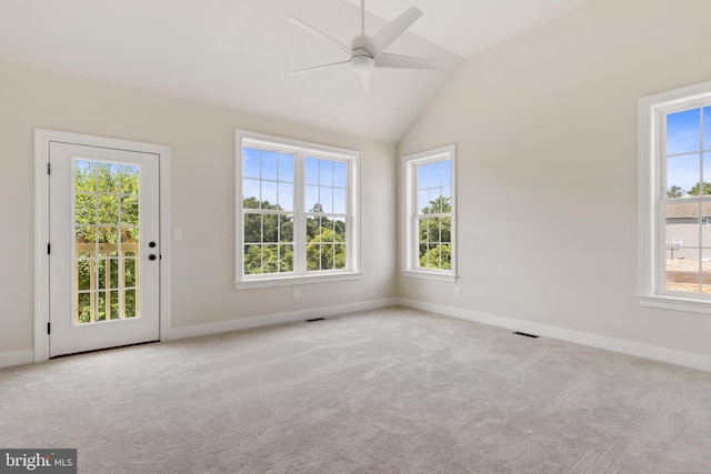 carpeted spare room featuring ceiling fan, vaulted ceiling, and plenty of natural light