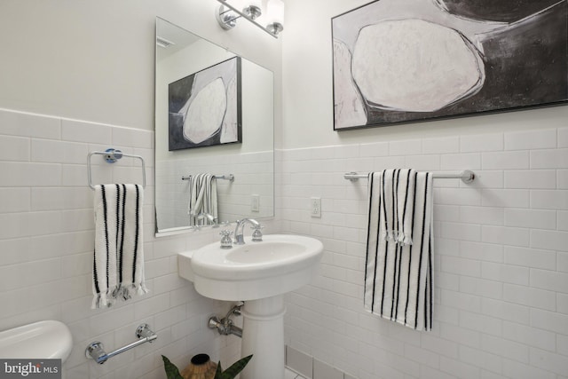 bathroom featuring toilet and tile walls