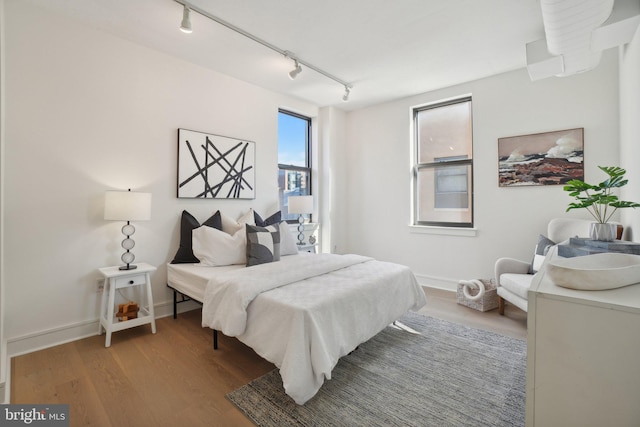 bedroom with rail lighting and hardwood / wood-style floors