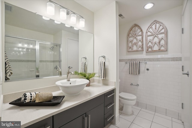 bathroom with tile patterned floors, vanity, tile walls, toilet, and walk in shower