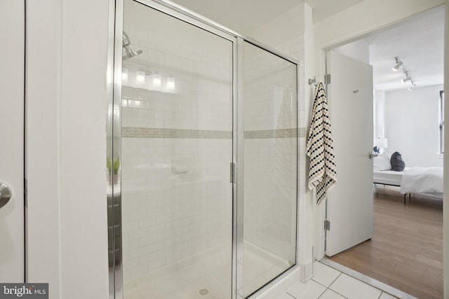 bathroom with a shower with door and tile patterned flooring