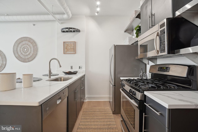 kitchen featuring sink, stainless steel appliances, light stone countertops, and light hardwood / wood-style floors