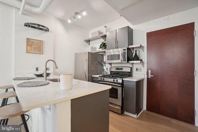 kitchen featuring kitchen peninsula, light hardwood / wood-style flooring, appliances with stainless steel finishes, sink, and a breakfast bar area