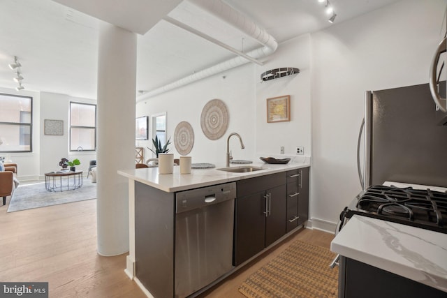 kitchen featuring appliances with stainless steel finishes, sink, light wood-type flooring, dark brown cabinets, and kitchen peninsula