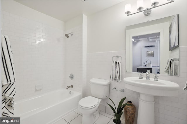 bathroom with toilet, tile walls, tiled shower / bath, and tile patterned flooring