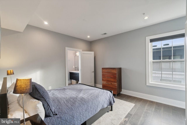 bedroom featuring ensuite bathroom and dark hardwood / wood-style floors