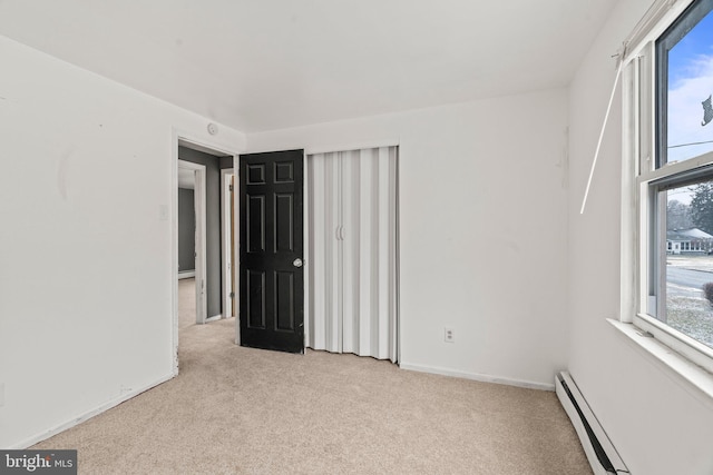 empty room with light colored carpet and a baseboard heating unit