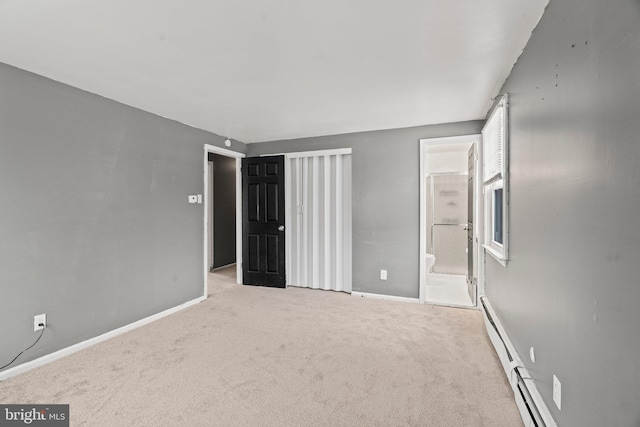 unfurnished bedroom featuring light colored carpet, ensuite bathroom, and baseboard heating