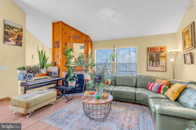 living room with a textured ceiling, lofted ceiling, and wood-type flooring