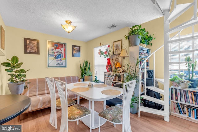 dining space with a textured ceiling and light hardwood / wood-style flooring