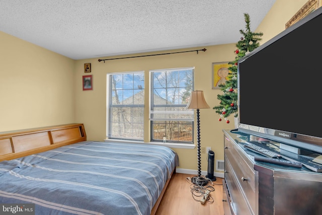 bedroom with a textured ceiling and light hardwood / wood-style flooring