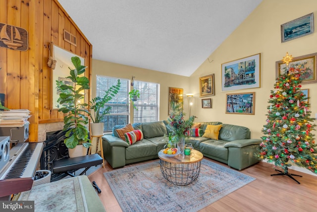 living room featuring wood-type flooring, vaulted ceiling, and a textured ceiling