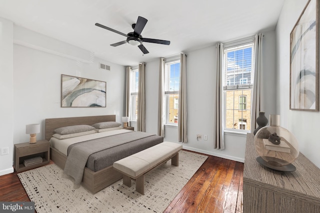 bedroom featuring multiple windows, dark hardwood / wood-style floors, and ceiling fan