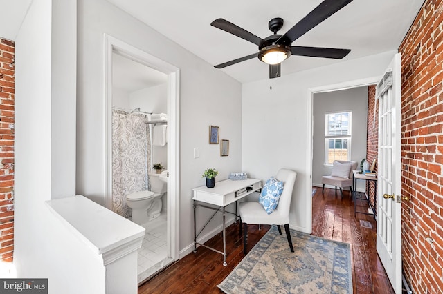 office with dark wood-type flooring, ceiling fan, and brick wall