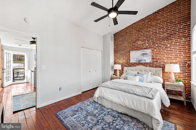 bedroom featuring ceiling fan, high vaulted ceiling, dark hardwood / wood-style floors, brick wall, and a closet