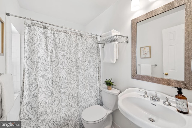 bathroom featuring a shower with curtain, sink, and toilet