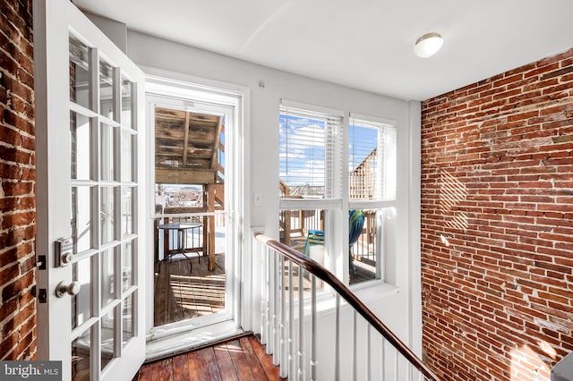 doorway with hardwood / wood-style flooring, brick wall, and french doors