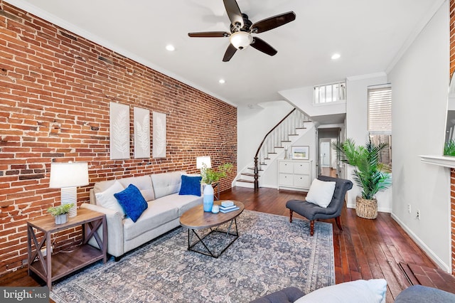 living room featuring ceiling fan, ornamental molding, brick wall, and dark hardwood / wood-style flooring