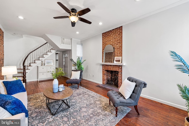 living room with ornamental molding, hardwood / wood-style floors, ceiling fan, and a fireplace