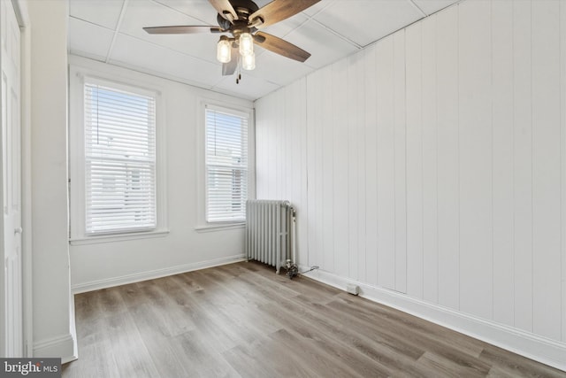 empty room with ceiling fan, radiator, and light hardwood / wood-style floors