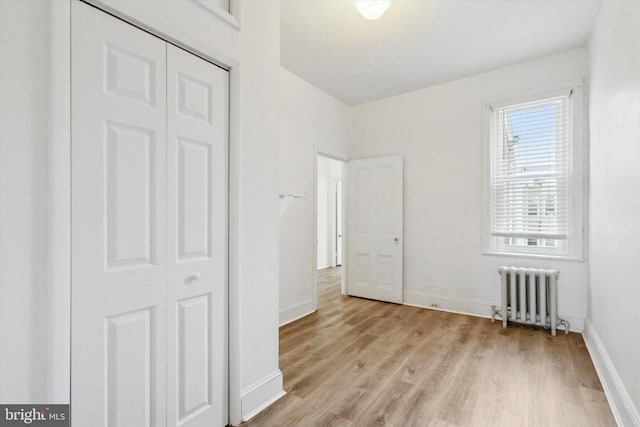 unfurnished bedroom featuring radiator, a closet, and light wood-type flooring