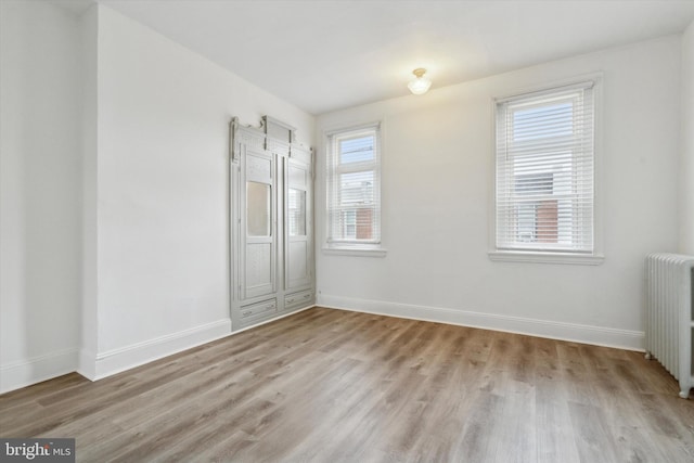 unfurnished room featuring light hardwood / wood-style floors and radiator