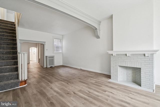 unfurnished living room with light hardwood / wood-style flooring and a brick fireplace