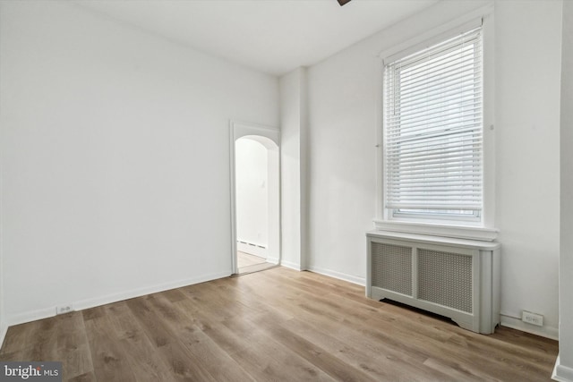 spare room featuring radiator and light wood-type flooring