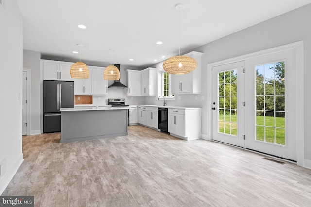 kitchen featuring appliances with stainless steel finishes, pendant lighting, white cabinets, and a kitchen island