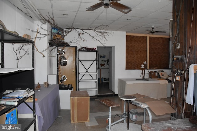 basement featuring ceiling fan and a drop ceiling