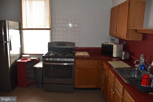 kitchen featuring light tile patterned flooring, sink, fridge, and stainless steel gas range oven