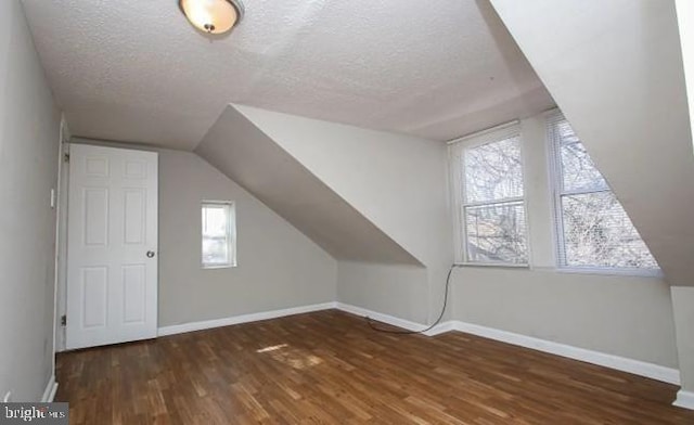 bonus room with vaulted ceiling, dark wood-type flooring, a textured ceiling, and a healthy amount of sunlight